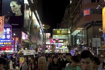 A bustling city street lit up at night, full of colorful lights and smiling travelers.