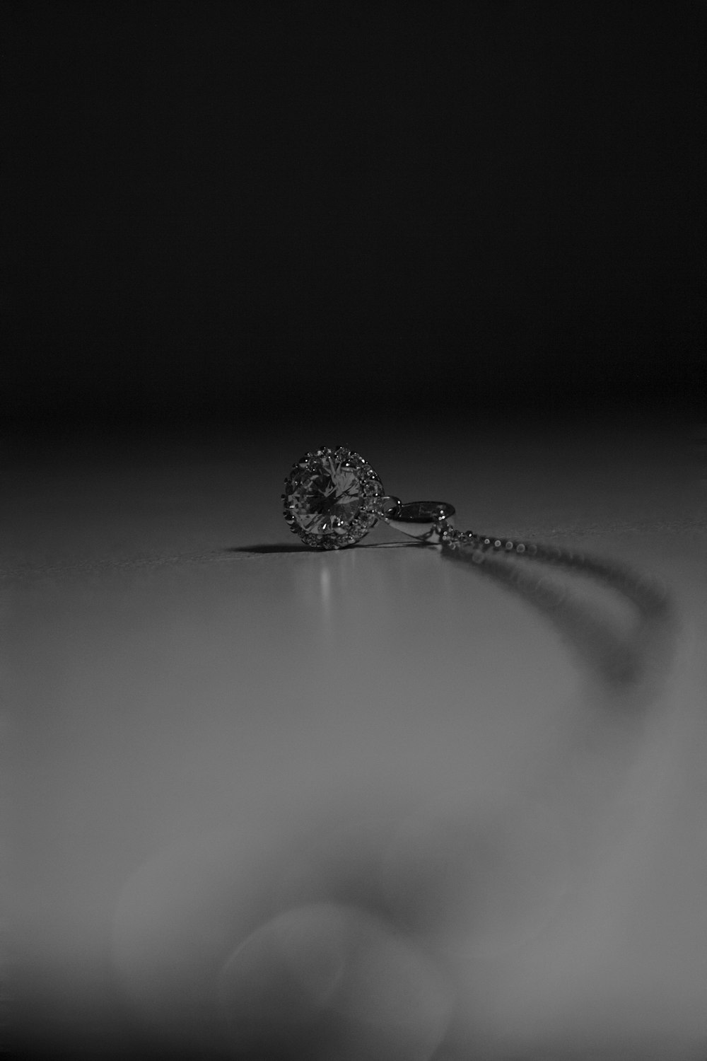 silver round pendant necklace in grayscale photography