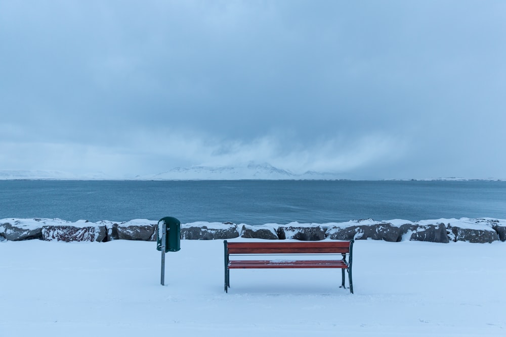 red wooden bench on snow covered ground during daytime