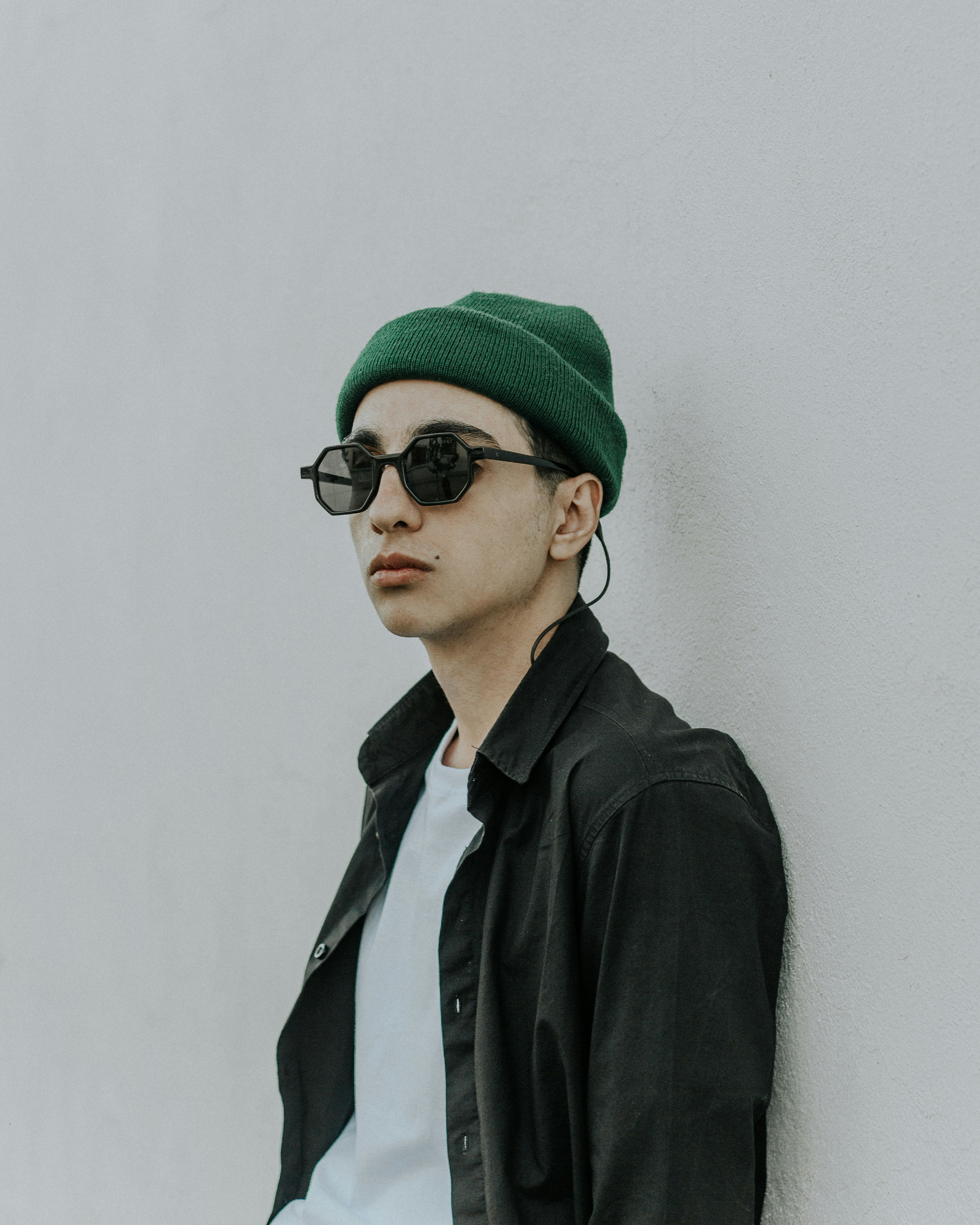 緑のニット帽と黒のサングラスを身に着けている黒いコートの男の写真 Unsplashで見つけるファッションの無料写真