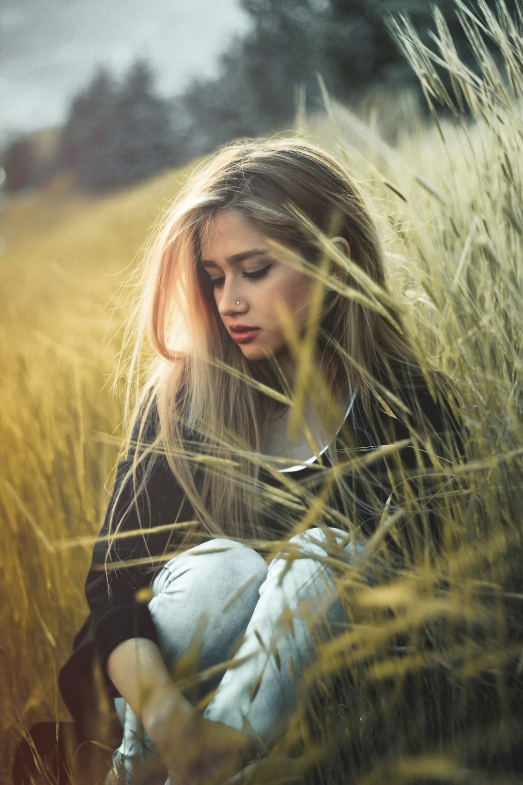 woman in black and white striped long sleeve shirt sitting on brown grass field during daytime