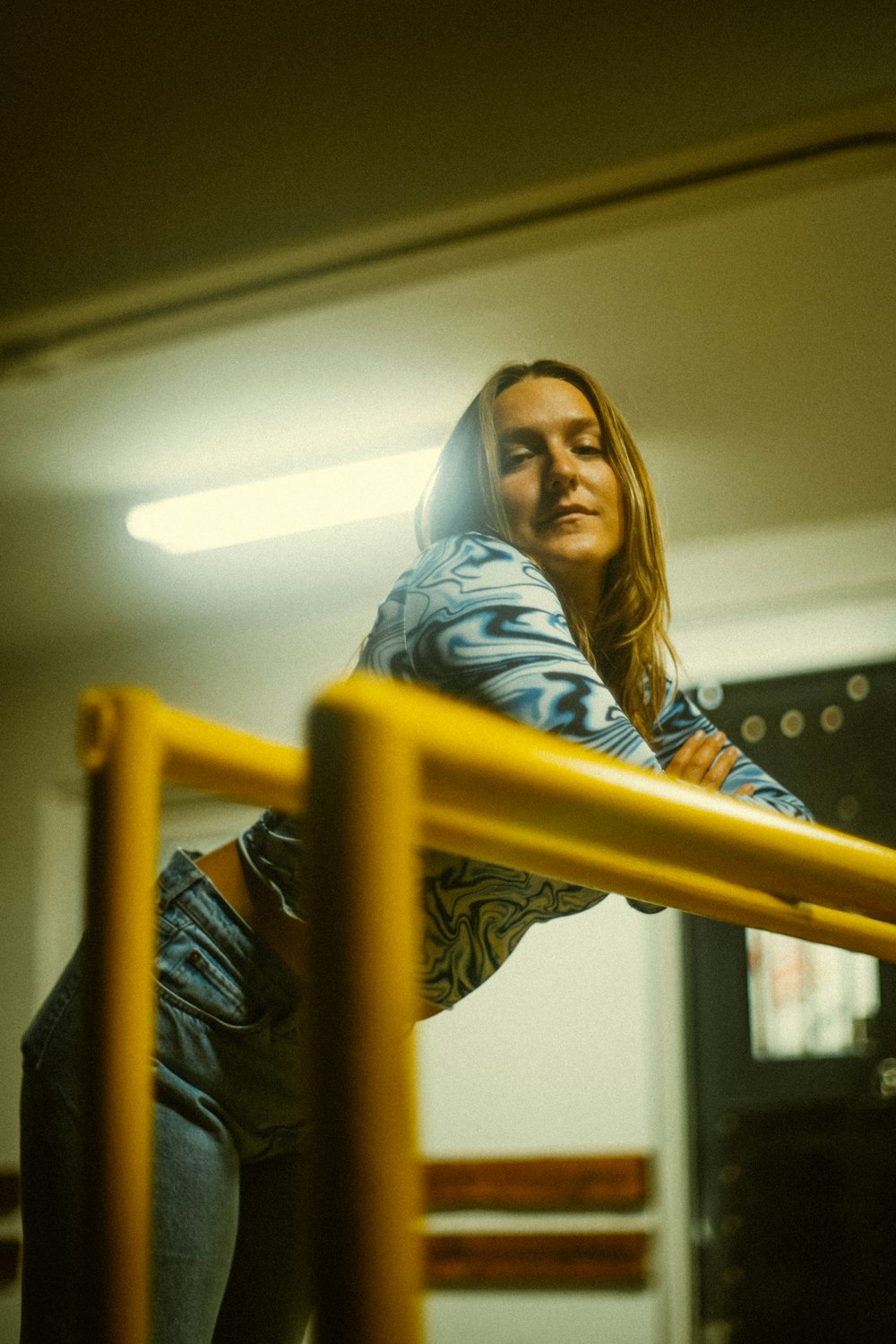 woman in blue denim jacket standing beside yellow metal railings