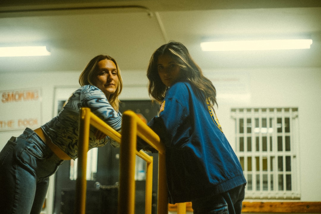 woman in blue denim jacket standing beside yellow metal railings