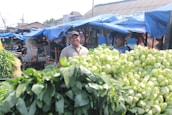 A smiling small-scale farmer sharing stories with customers at a vibrant outdoor stall.