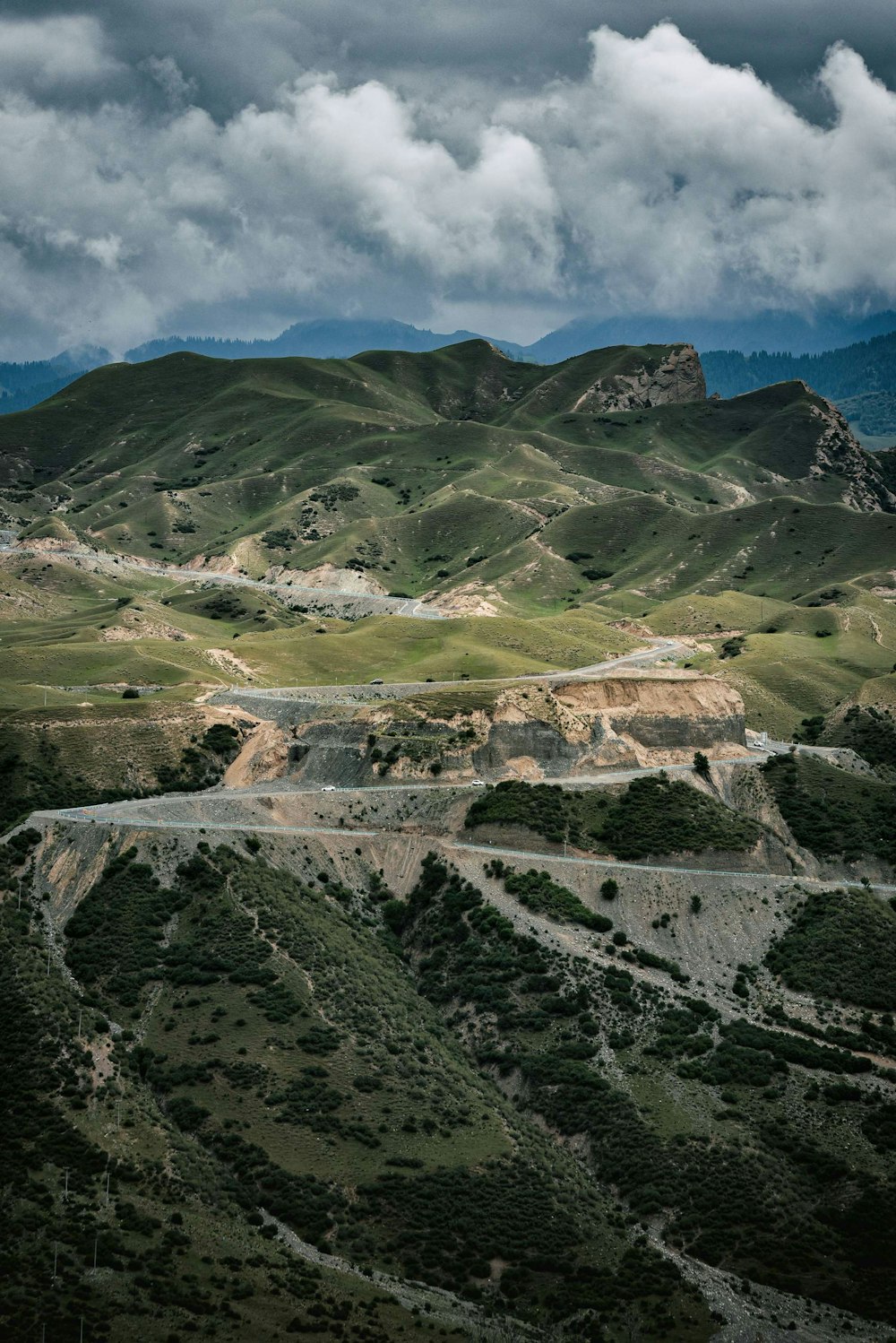 montañas verdes y marrones bajo nubes blancas durante el día