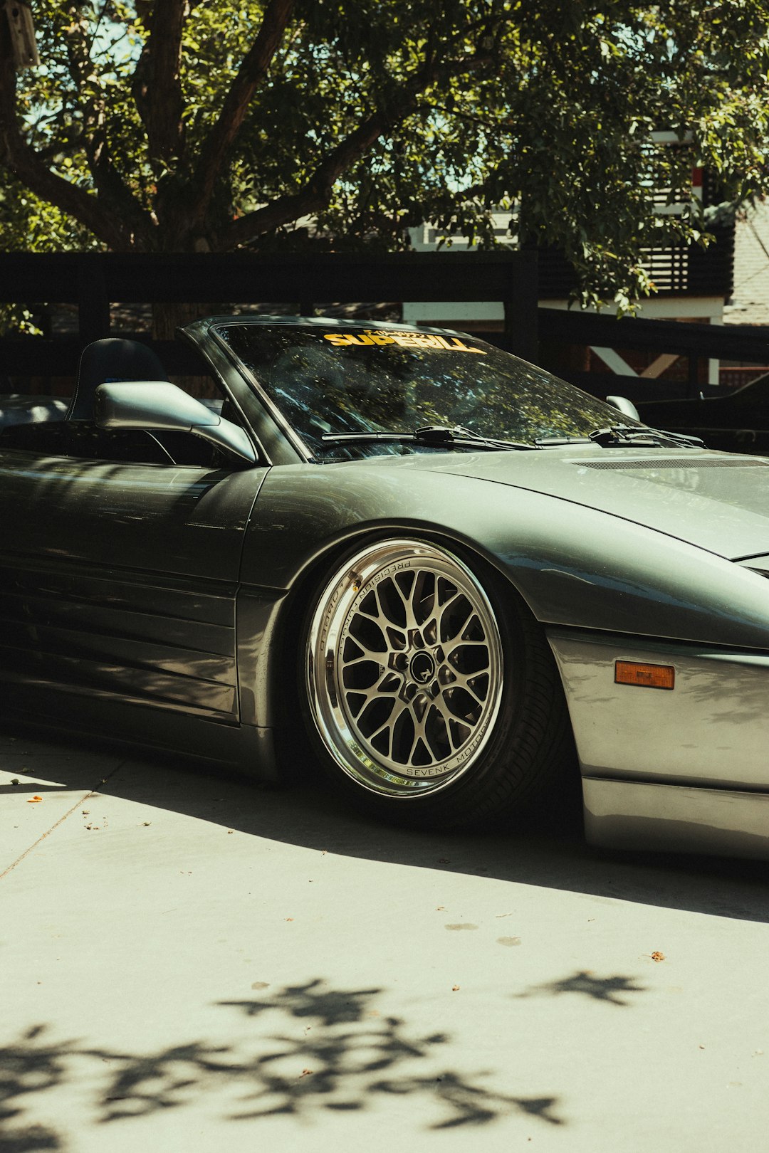 black porsche 911 parked near green tree during daytime