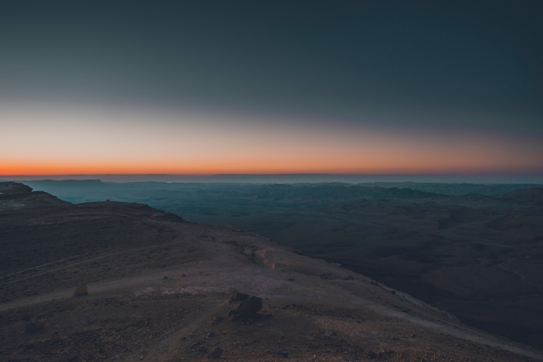 brown sand near body of water during sunset