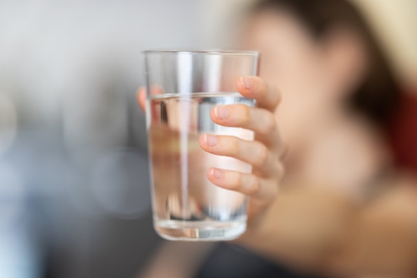 Hands holding a clear glass of water with a dissolved bioceuticals powder supplement.