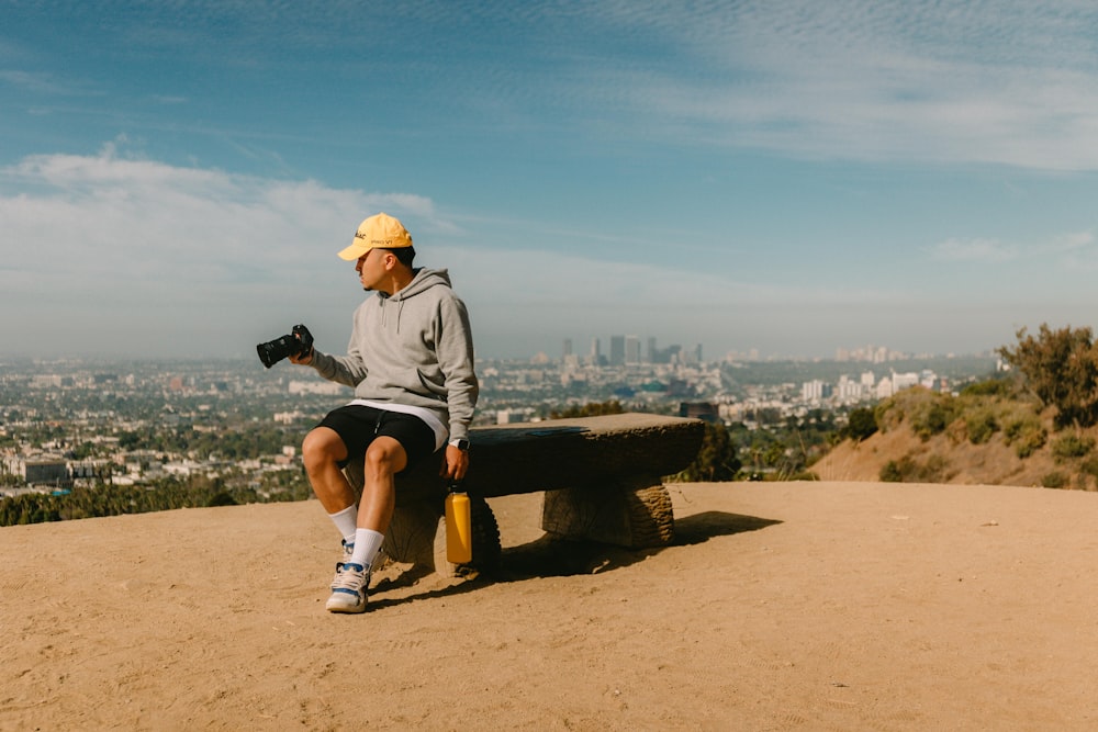 man in gray t-shirt and black shorts sitting on brown wooden bench during daytime