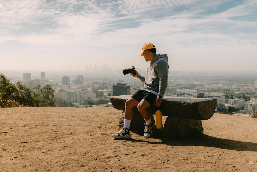 man in gray long sleeve shirt and black shorts sitting on brown wooden bench during daytime