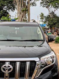 A sleek Toyota car parked on a city street with Indonesian people nearby.