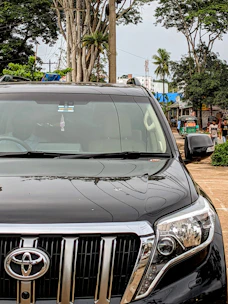 A sleek Toyota car parked on a city street with Indonesian people nearby.