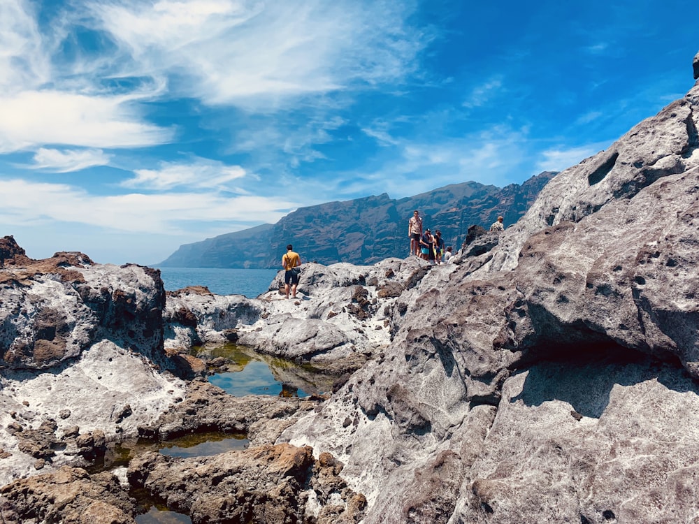 a group of people standing on top of a rocky cliff