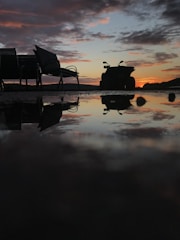 Quad bike silhouetted against a vibrant Sahara sunset with orange and pink skies.