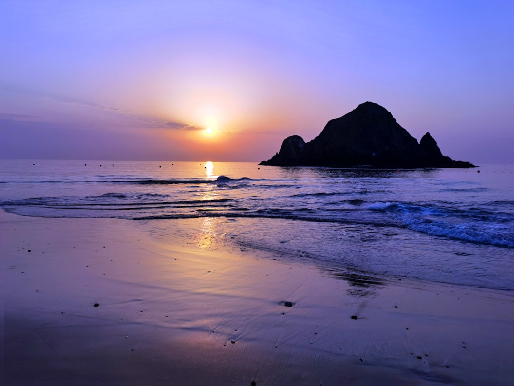 silhouette of mountain on sea during sunset