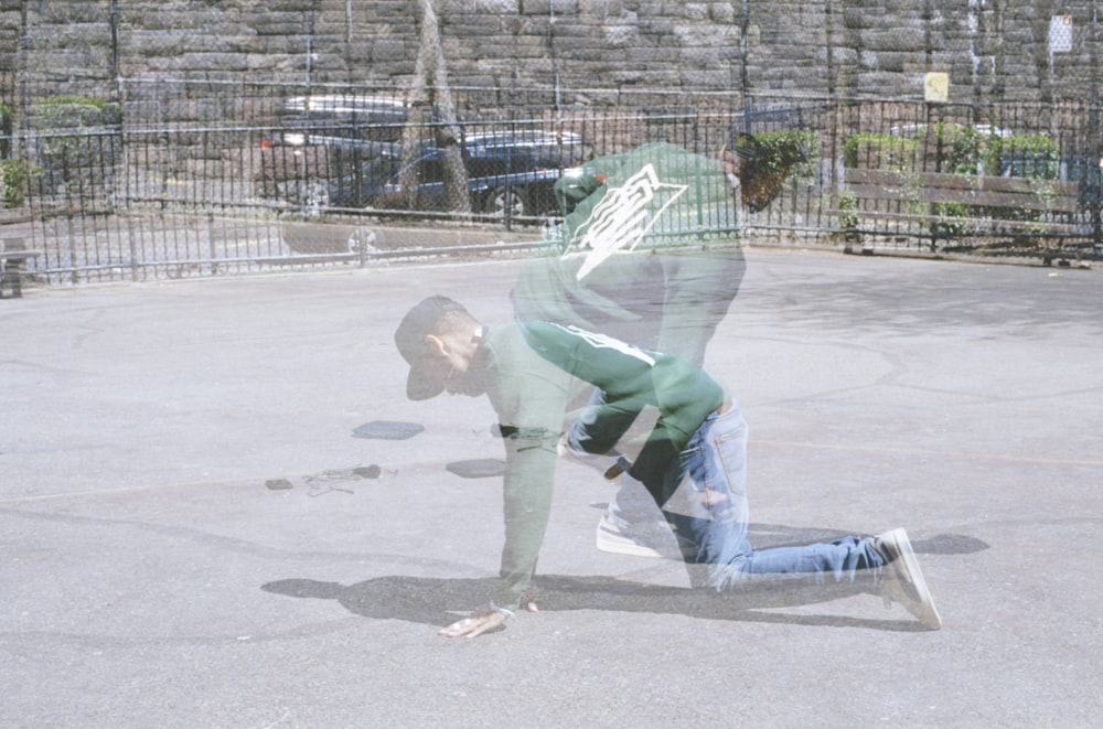 man in green shirt and blue denim jeans standing on gray concrete floor during daytime