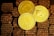 Three golden cryptocurrency coins are displayed on a textured surface resembling small brown bricks. The coins represent Bitcoin, Dogecoin, and Ethereum, each bearing their distinct symbols and inscriptions.