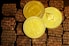 Three golden cryptocurrency coins are displayed on a textured surface resembling small brown bricks. The coins represent Bitcoin, Dogecoin, and Ethereum, each bearing their distinct symbols and inscriptions.