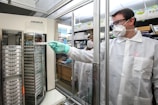 man in white scrub suit standing near glass window