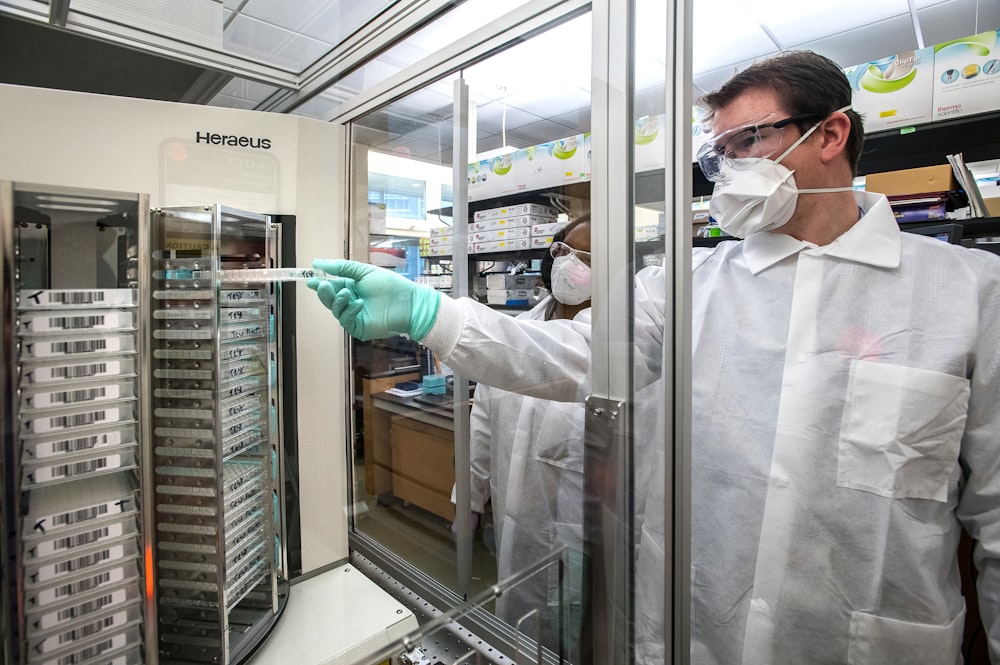 man in white scrub suit standing near glass window