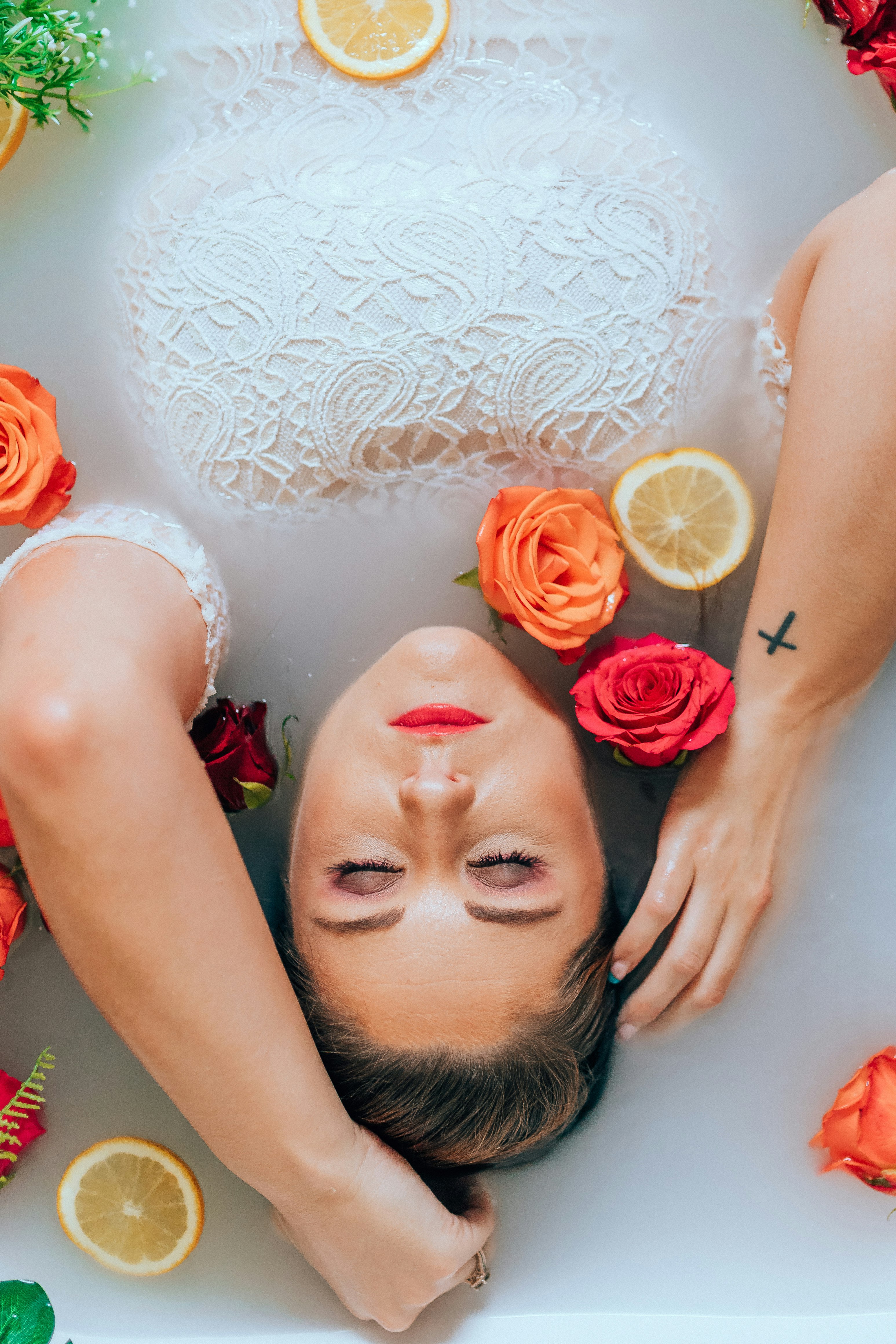 woman in white floral dress holding red rose bouquet