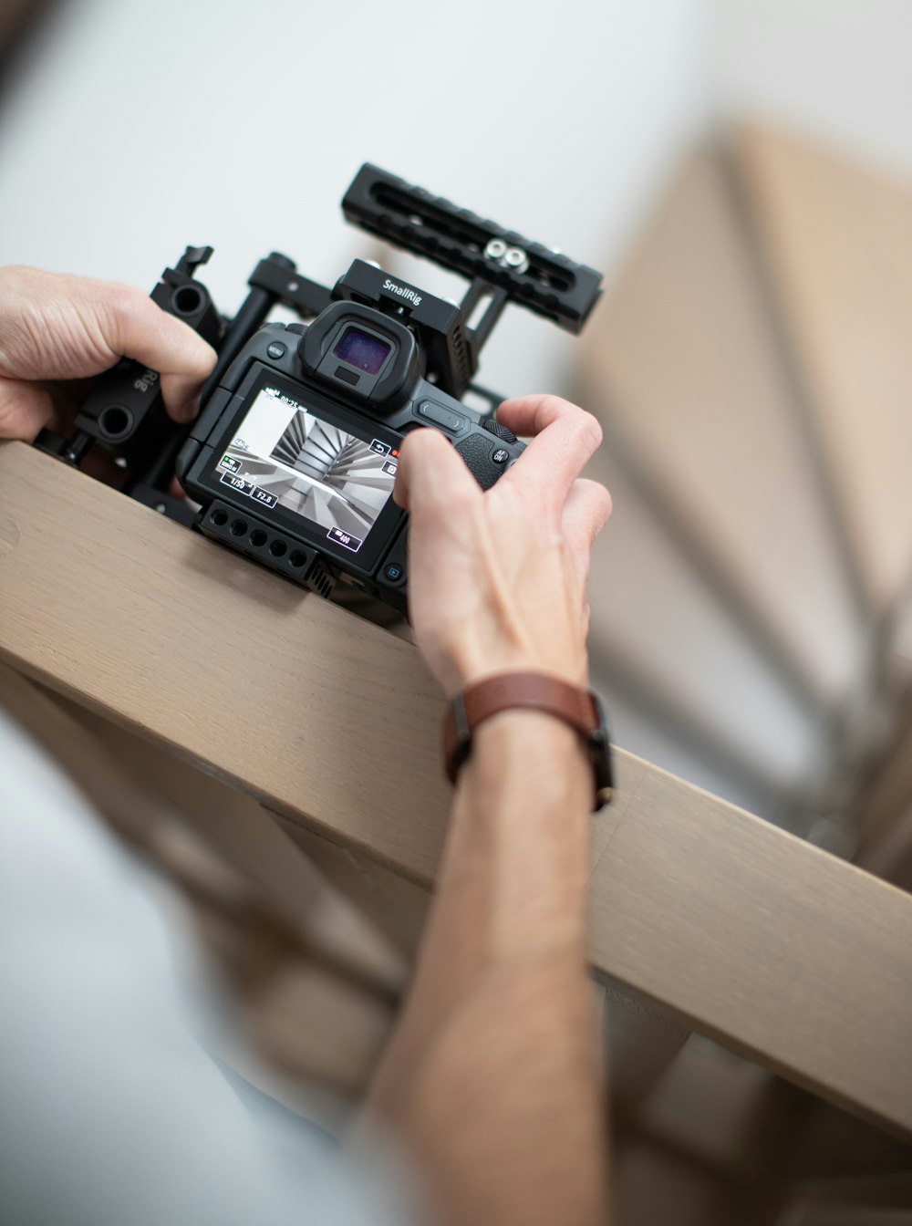 person holding black camera on brown wooden table