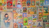 A collage of vintage Chinese posters and advertisements with colorful and intricate designs. The posters feature a variety of images including traditional symbols, animals like roosters and dragons, and a portrait of a woman in a traditional dress holding flowers. The images are arranged tightly together, covering a wall, with an aged and nostalgic aesthetic.