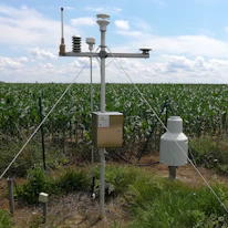 Close-up of advanced agricultural sensors installed in a green crop field.