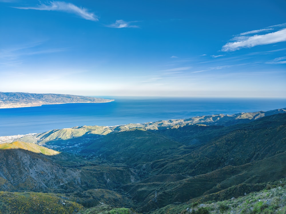 green mountains near body of water under blue sky during daytime