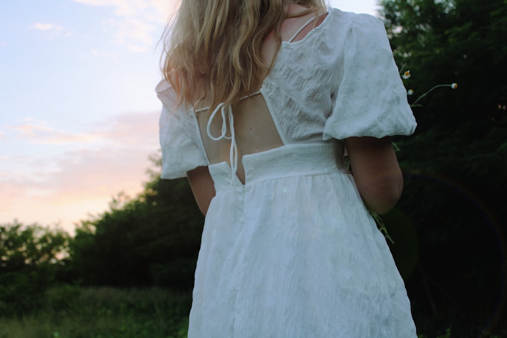 girl in white dress standing on green grass field during daytime