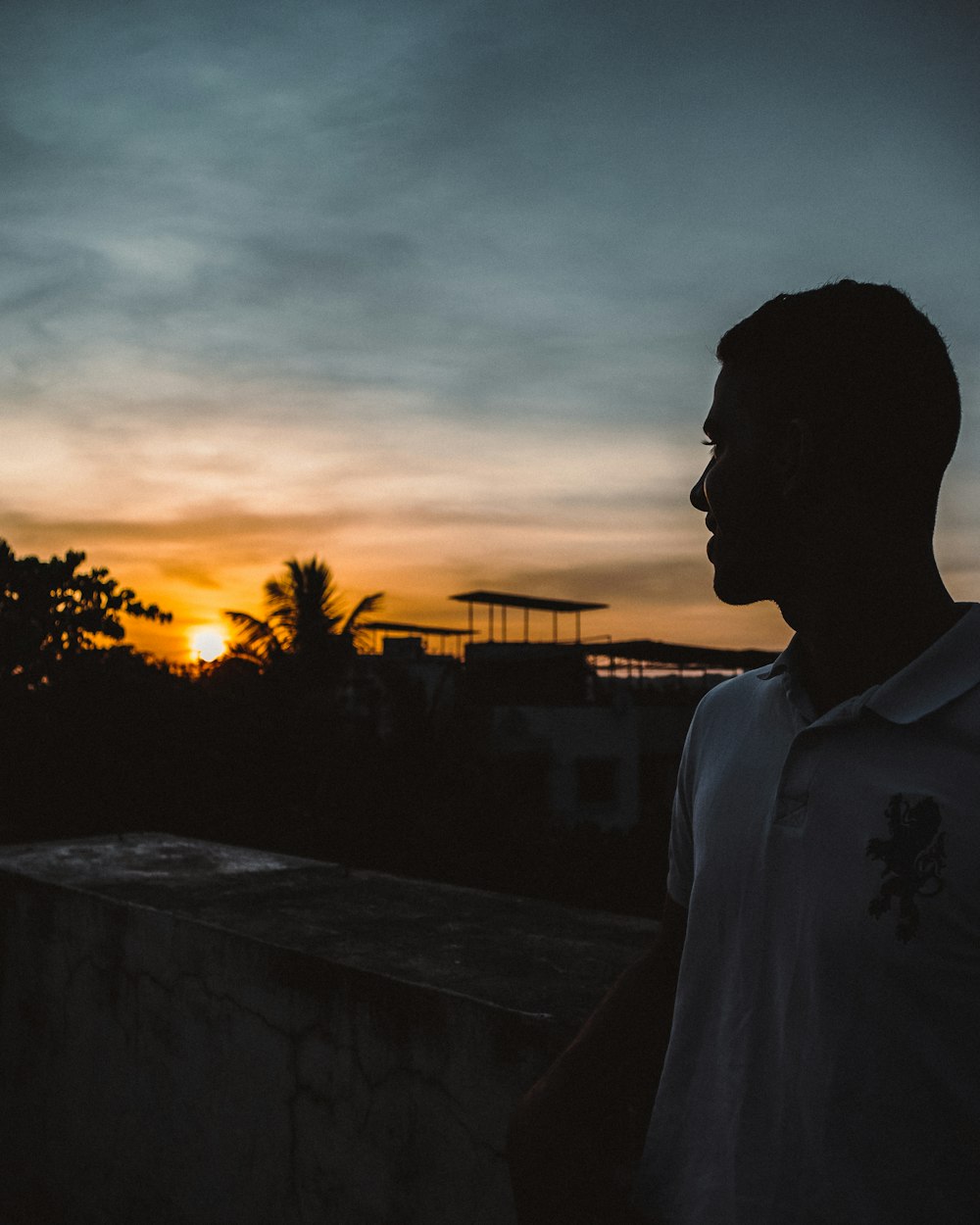 man in white shirt standing near trees during sunset