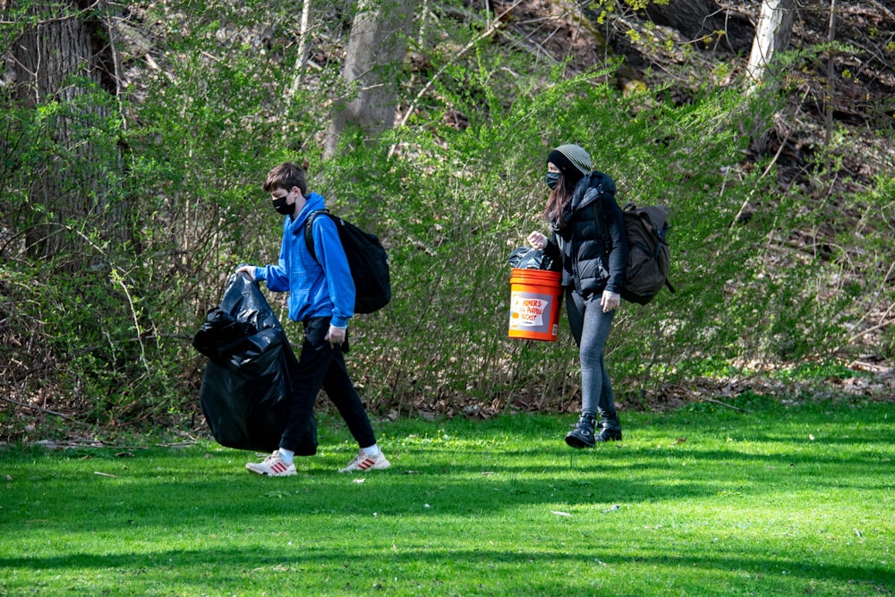 man in black jacket and blue backpack standing on green grass field during daytime