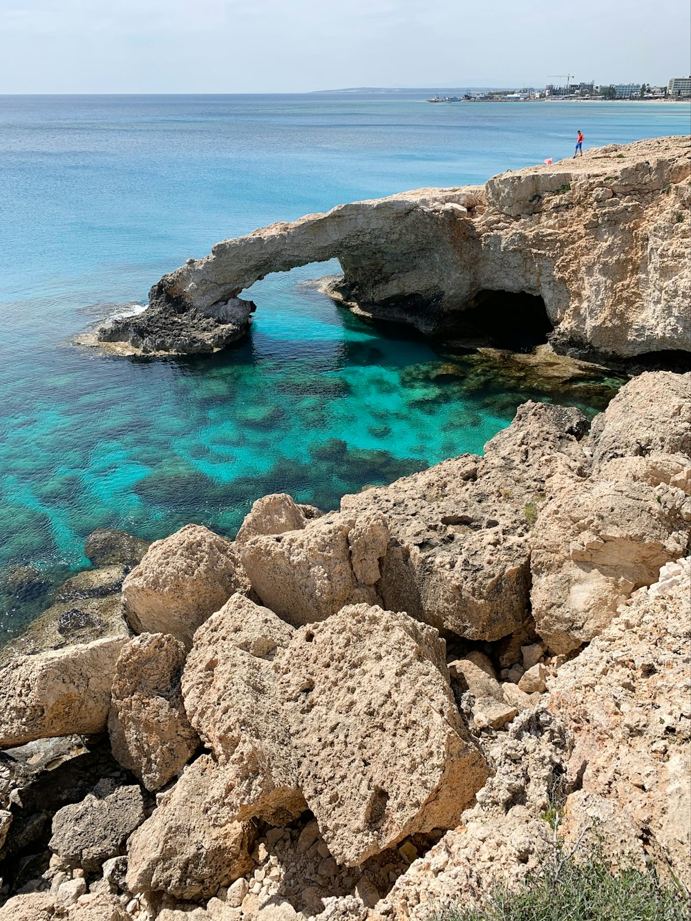 Persona in piedi sulla formazione rocciosa vicino allo specchio d'acqua durante il giorno