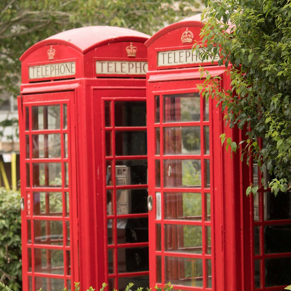 red telephone booth near green leaf tree during daytime