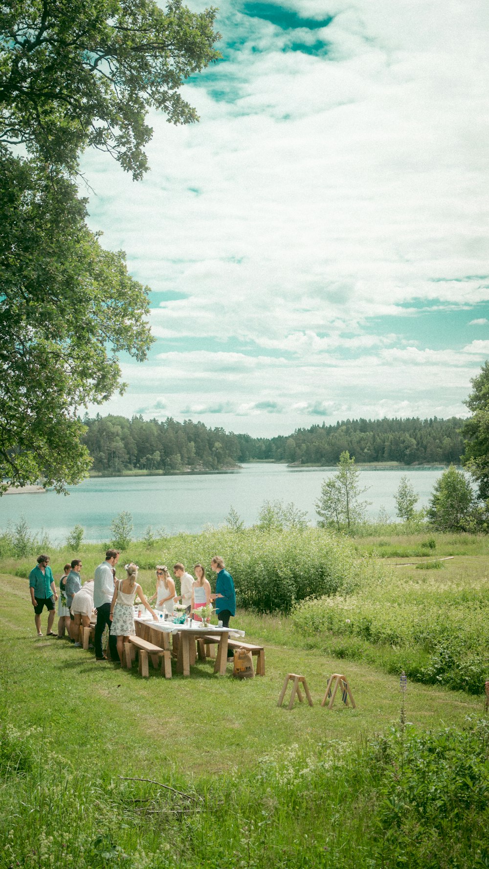 Menschen, die tagsüber auf einer braunen Holzbank in der Nähe des Sees sitzen
