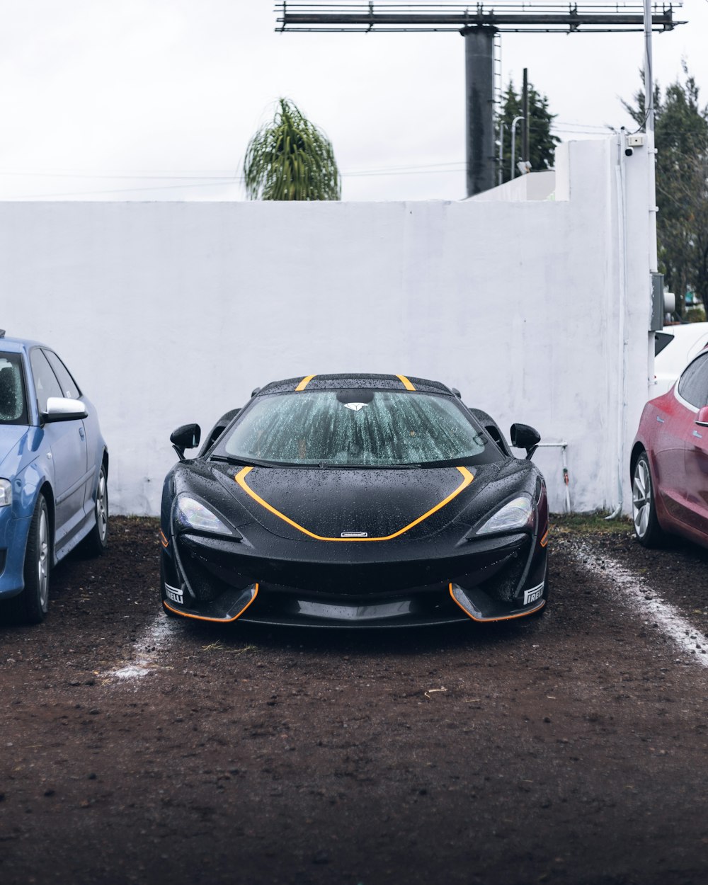 black and orange lamborghini aventador parked beside white wall