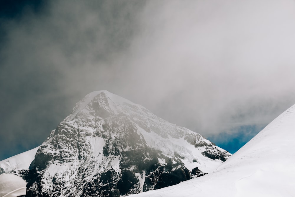 snow covered mountain under cloudy sky