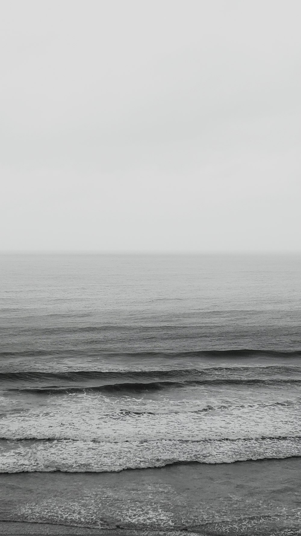 ocean waves under white sky during daytime