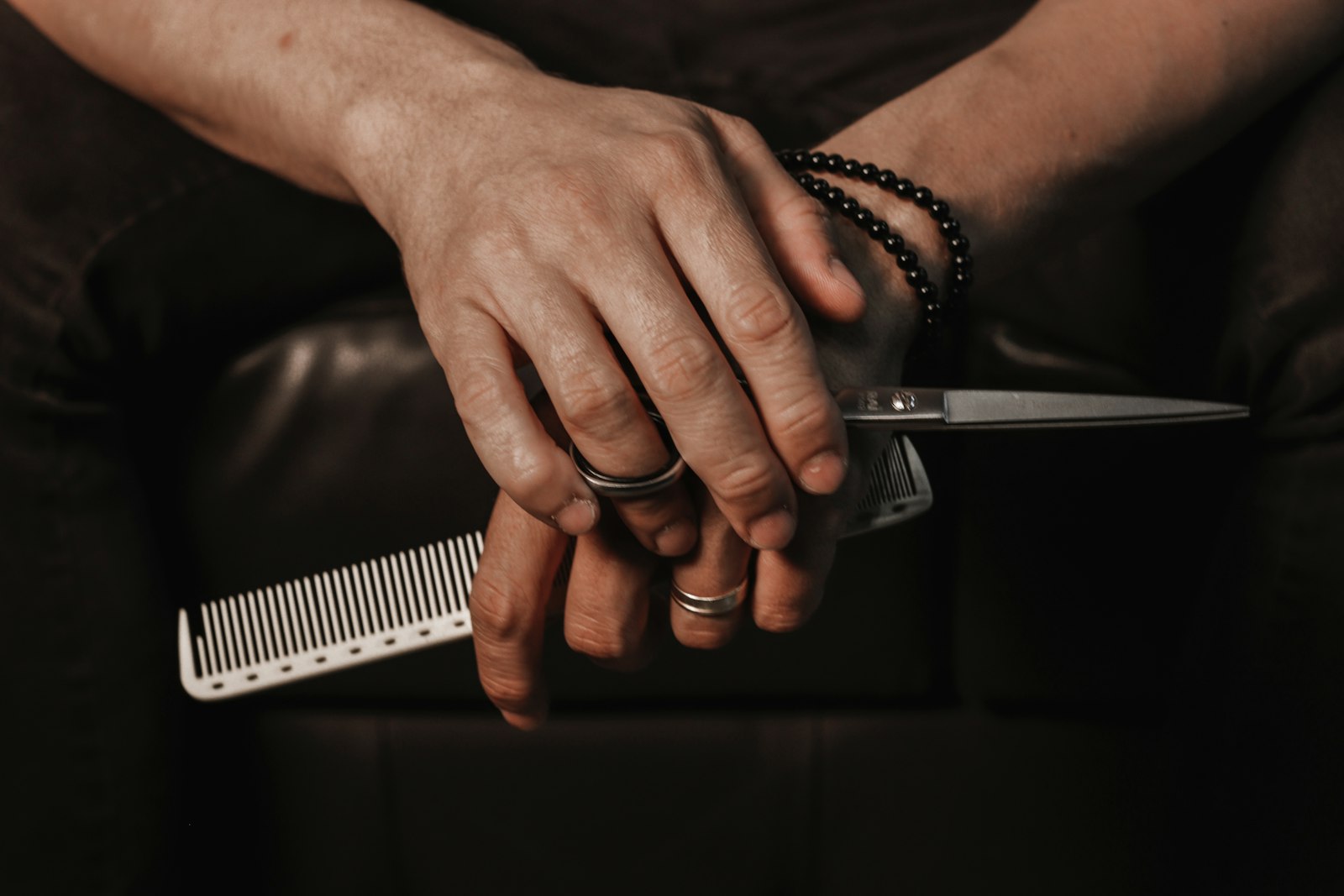 Barber's hands resting with comb and scissors