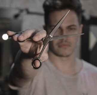 person holding black handled scissors