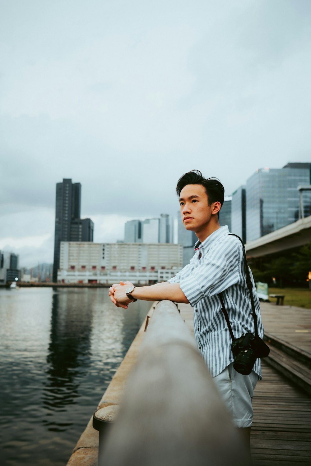 man in white and black plaid dress shirt sitting on brown wooden dock during daytime