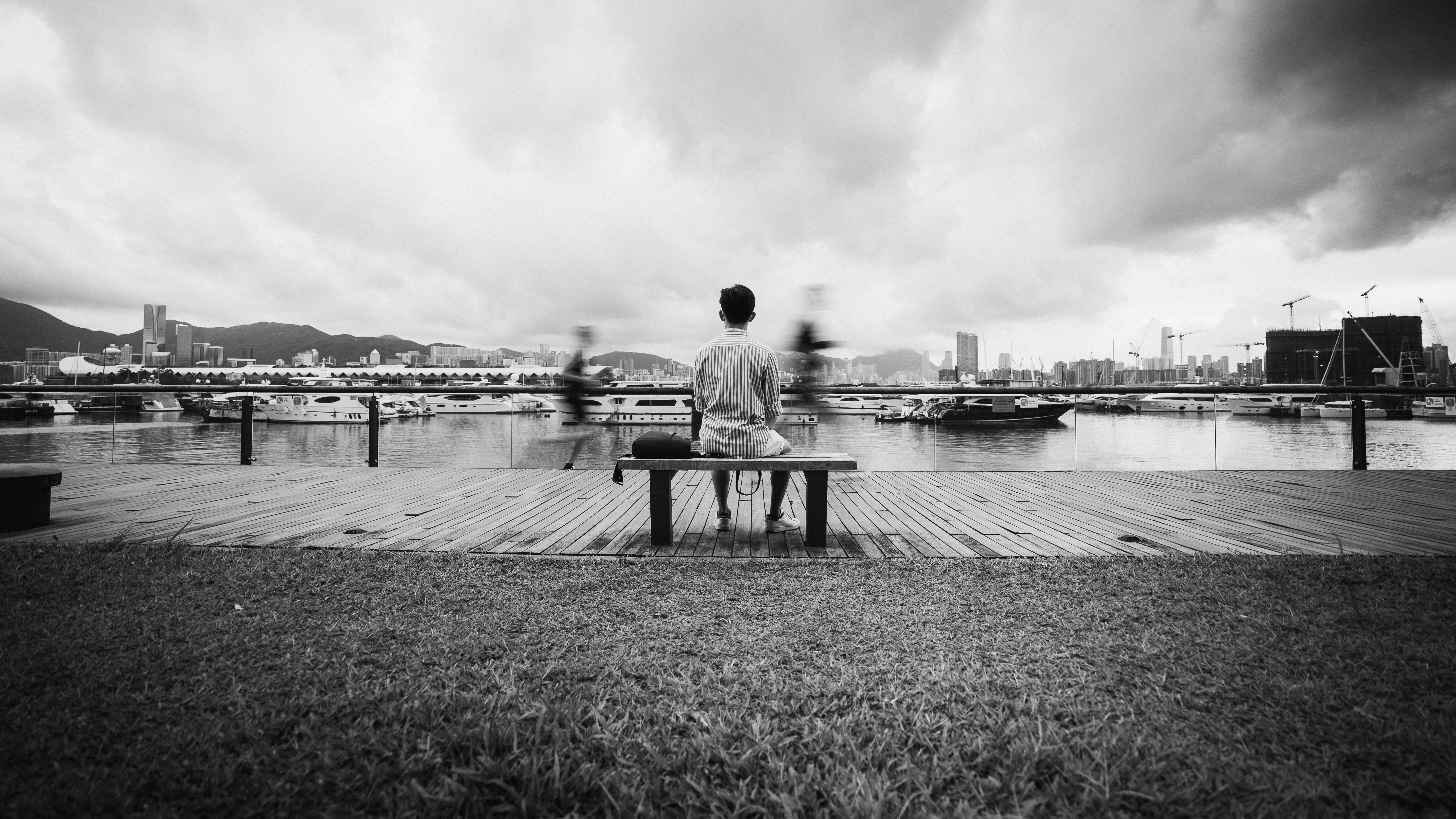 man sitting on bench near body of water