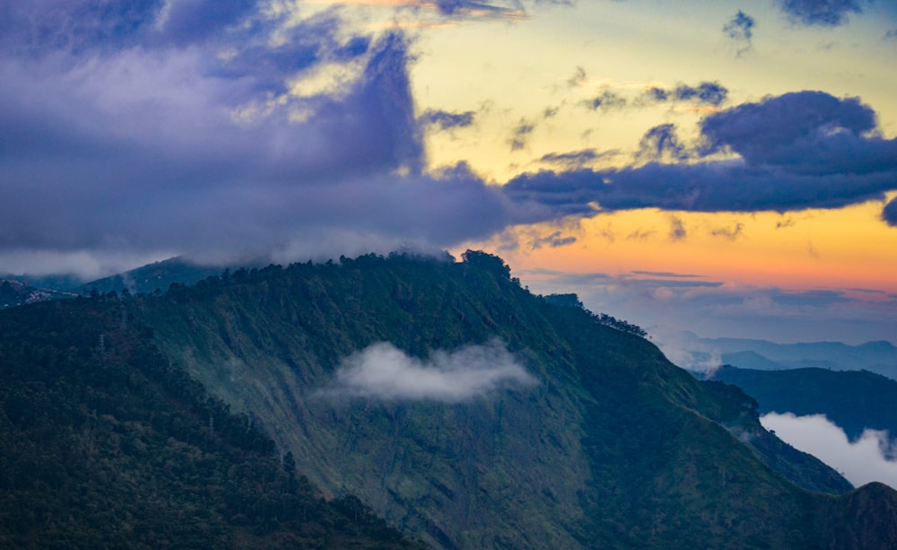 green and black mountain under white clouds during daytime