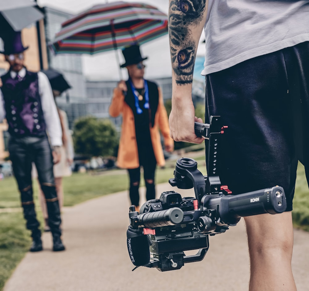 person in black shorts holding black dslr camera during daytime