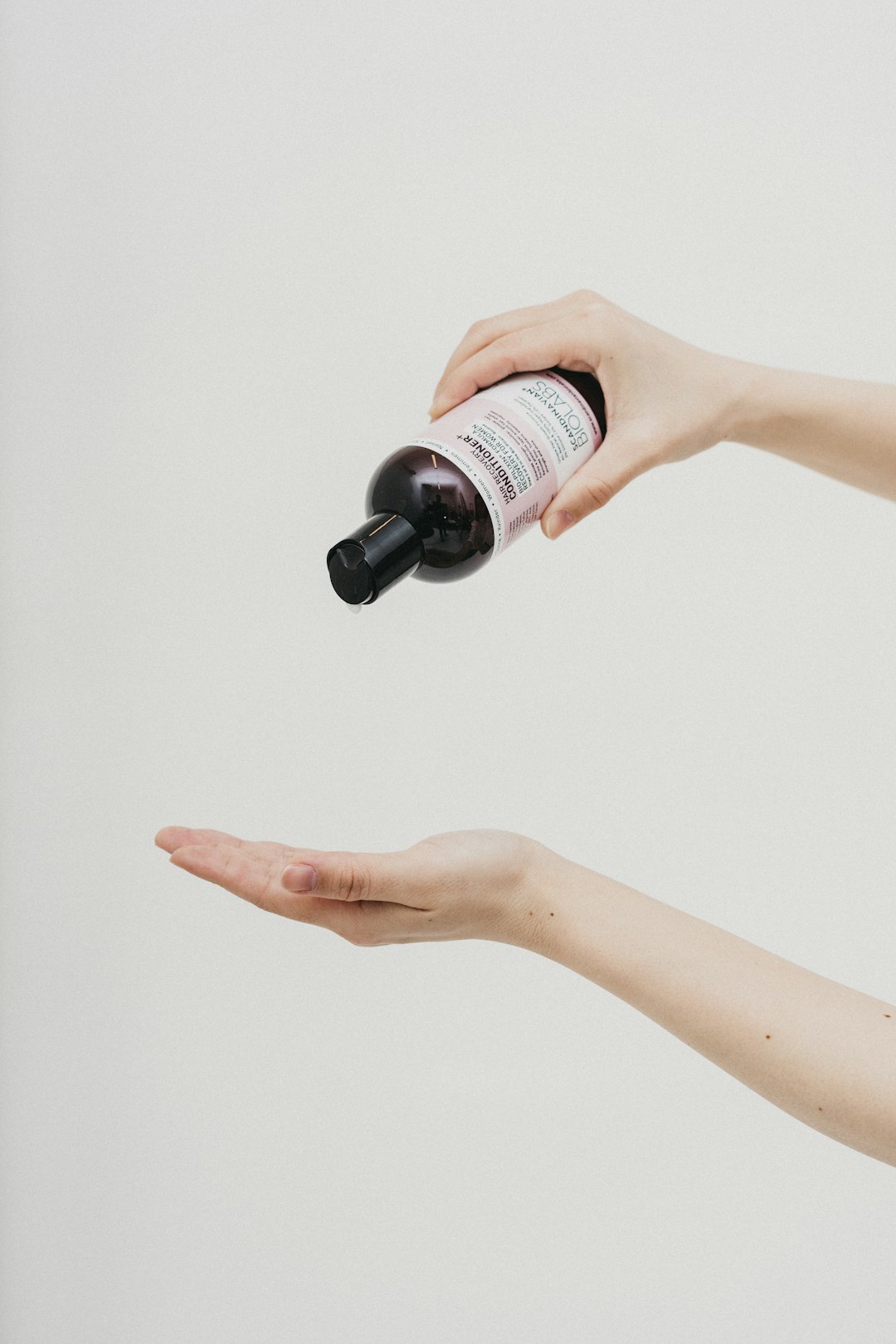 person holding white and black labeled bottle