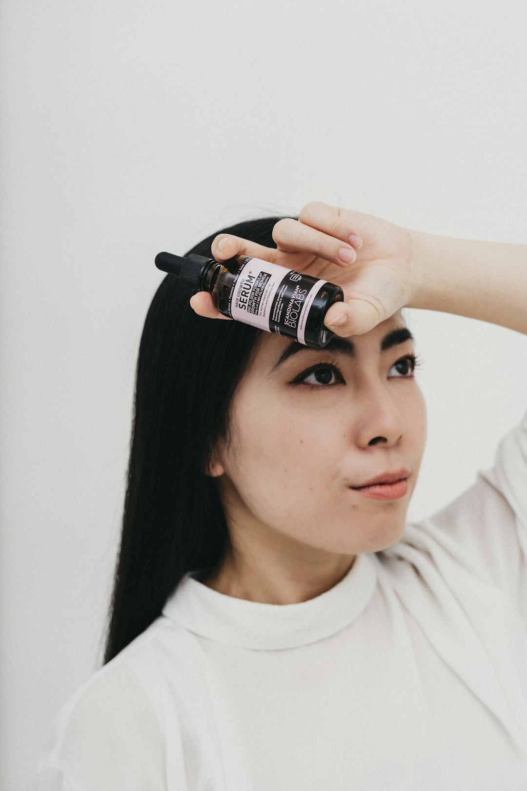 woman in white crew neck shirt holding black and white labeled bottle