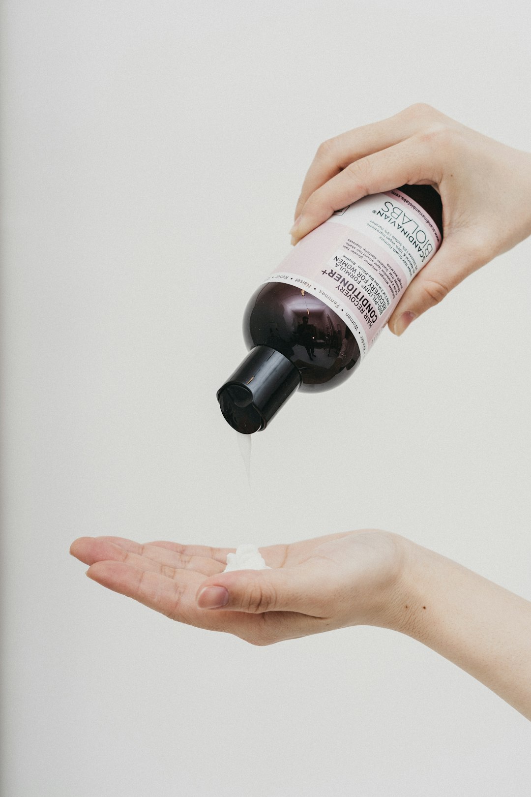 person holding white and black labeled bottle