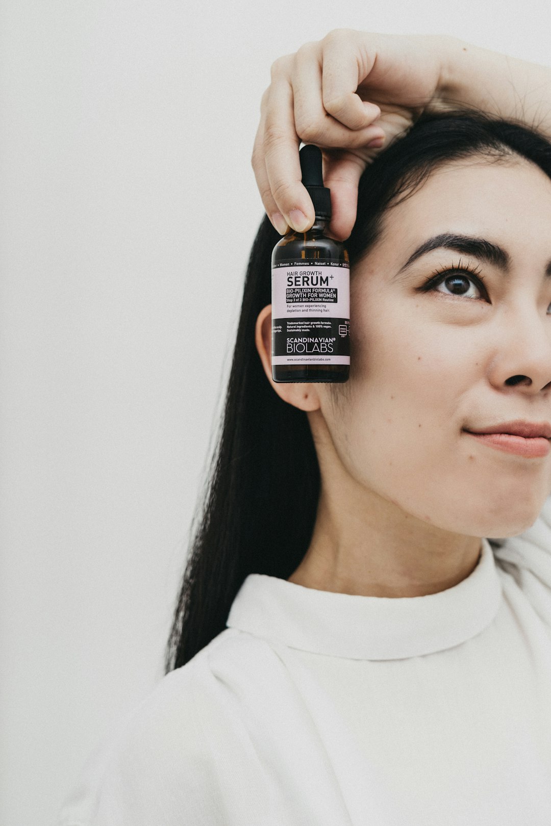 woman in white crew neck shirt holding black and white bottle