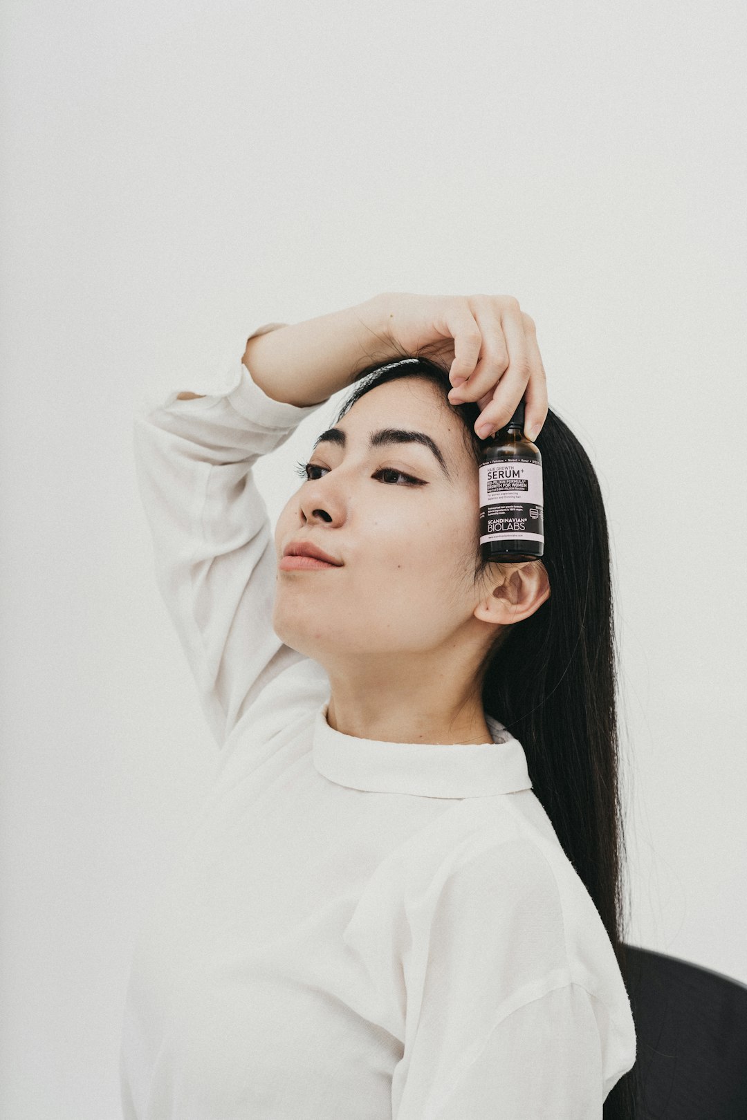 woman in white crew neck shirt holding black and white labeled bottle