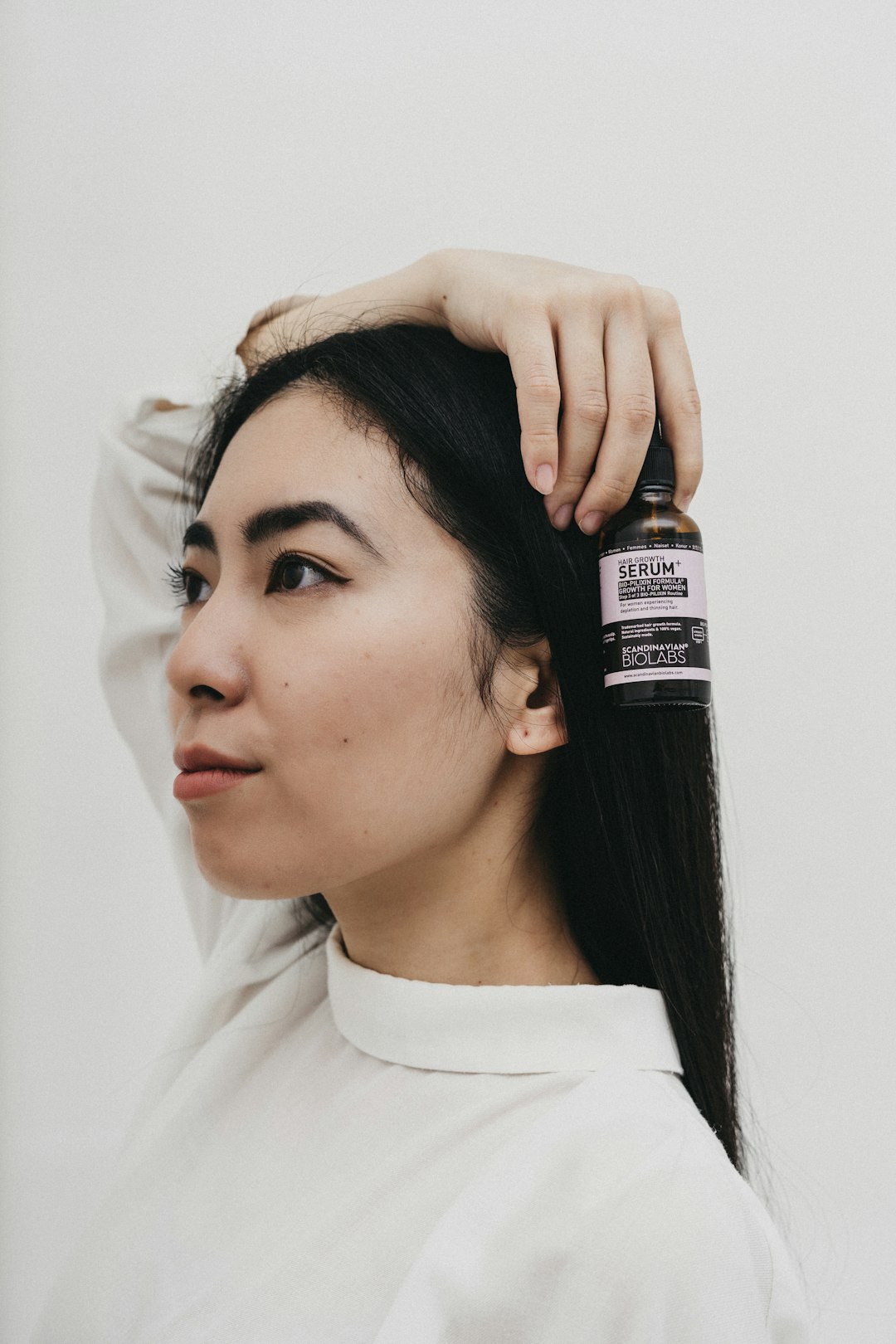 woman in white collared shirt holding black and white labeled bottle